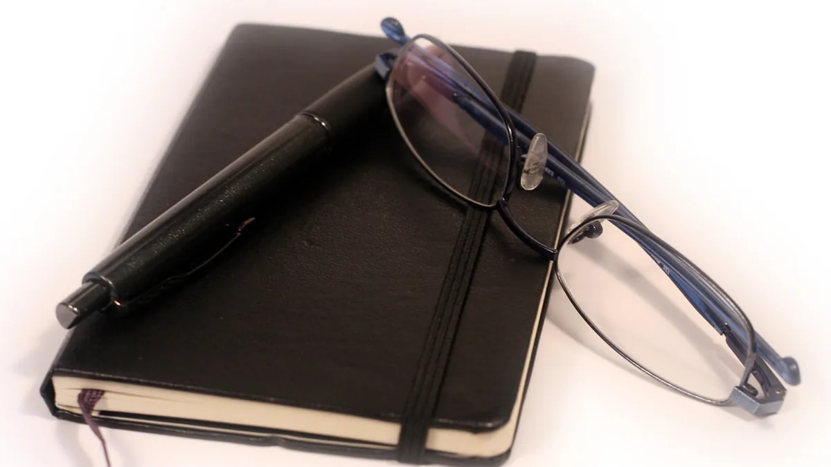 Notebook with pen and glasses on a desk — planning your review strategy takes structure, not guesswork