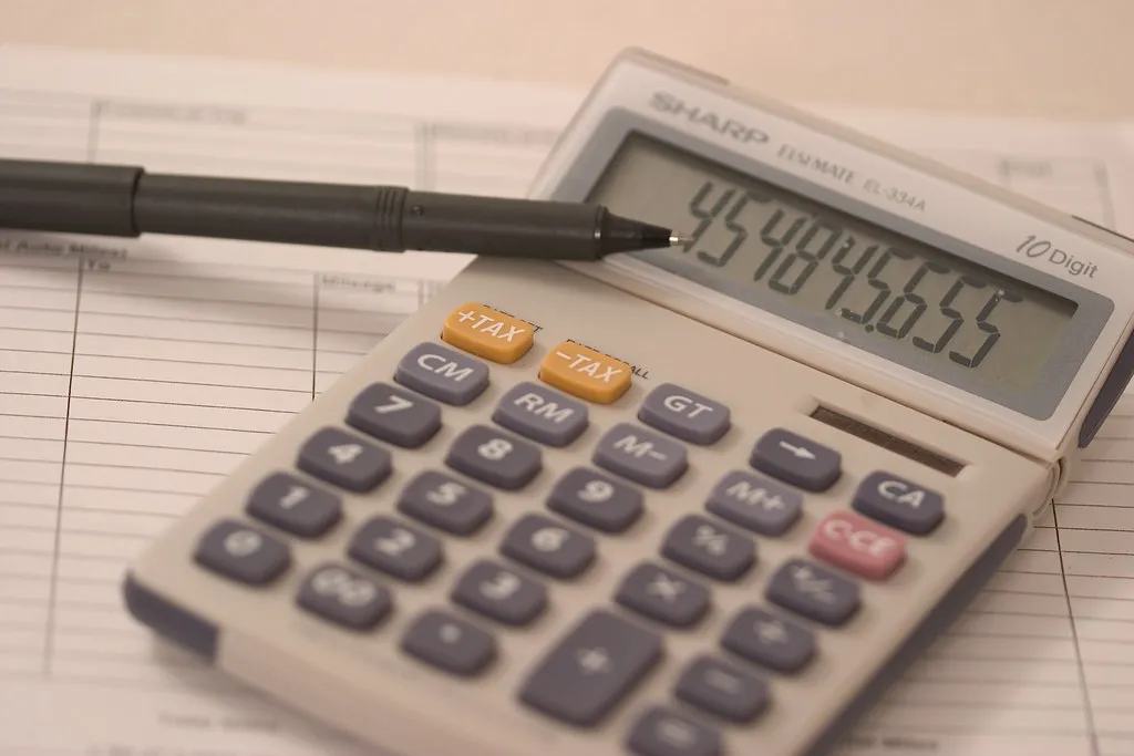 Calculator and pen on financial ledger for moving company cost analysis
