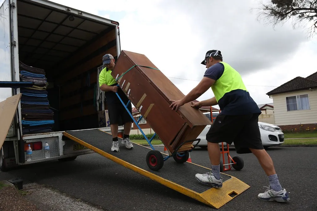Movers loading boxes onto a moving truck via ramp